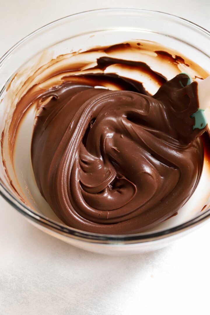 whipped milk chocolate frosting in a bowl with spatula