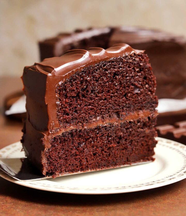 slice of milk chocolate cake upright on a plate with cake server