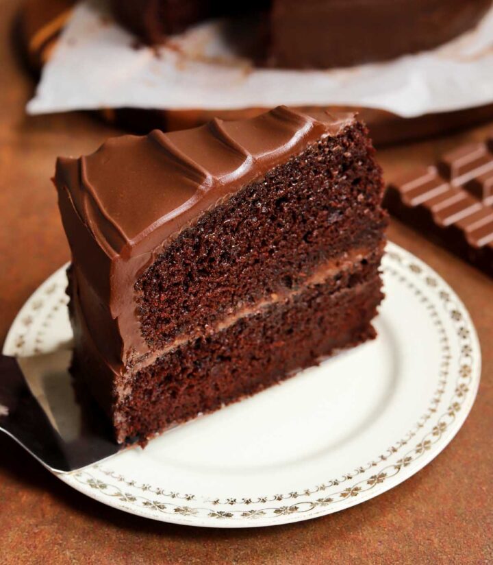 slice of milk chocolate cake on a plate with cake server