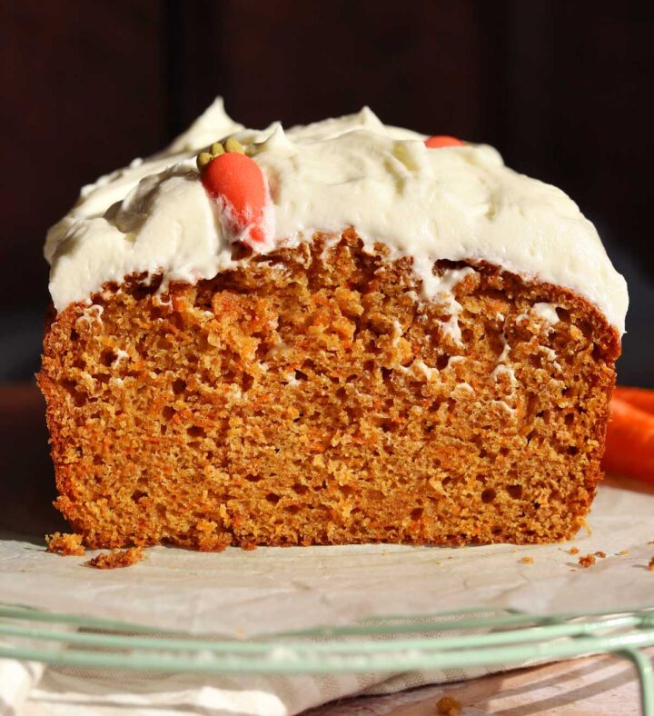 carrot cake loaf cake sliced on cooling rack with cream cheese frosting