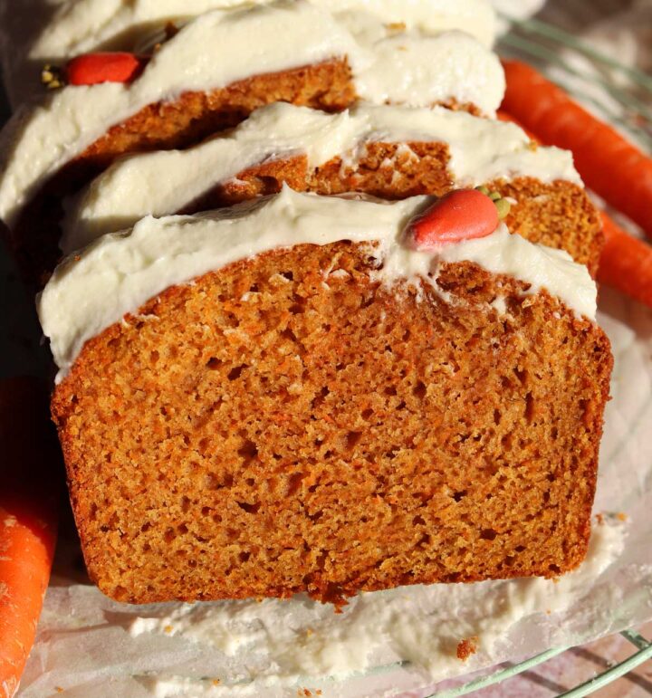 carrot cake loaf cake sliced on cooling rack with cream cheese frosting