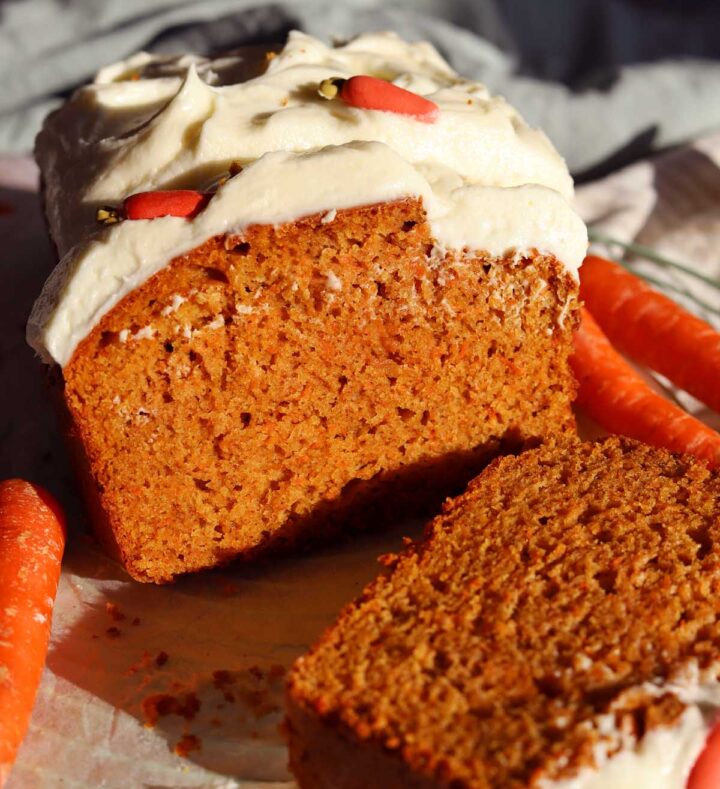 carrot cake loaf cake sliced on cooling rack with cream cheese frosting