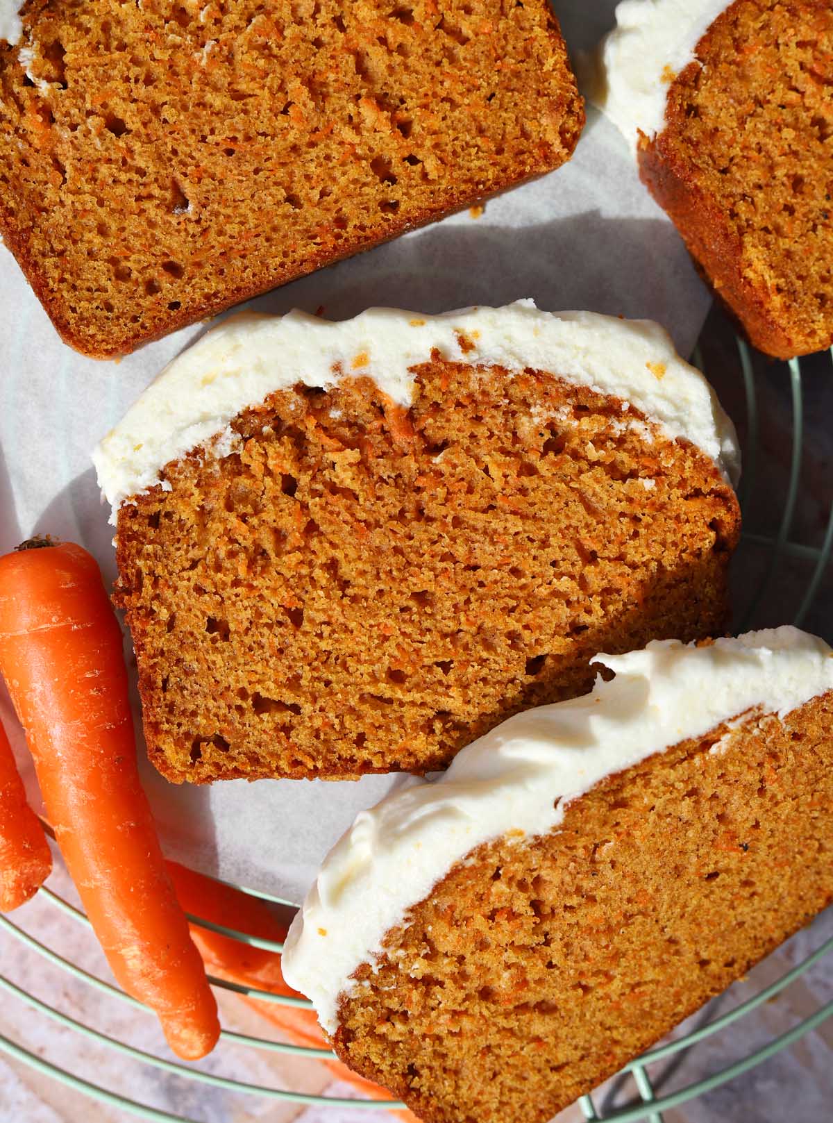 carrot cake loaf cake sliced on cooling rack with cream cheese frosting