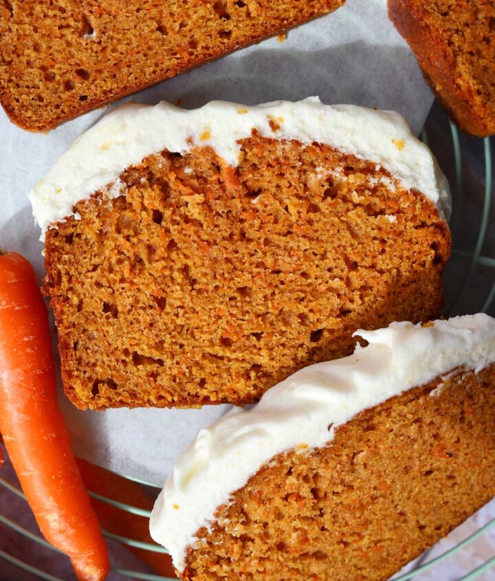 carrot cake loaf cake sliced on cooling rack with cream cheese frosting