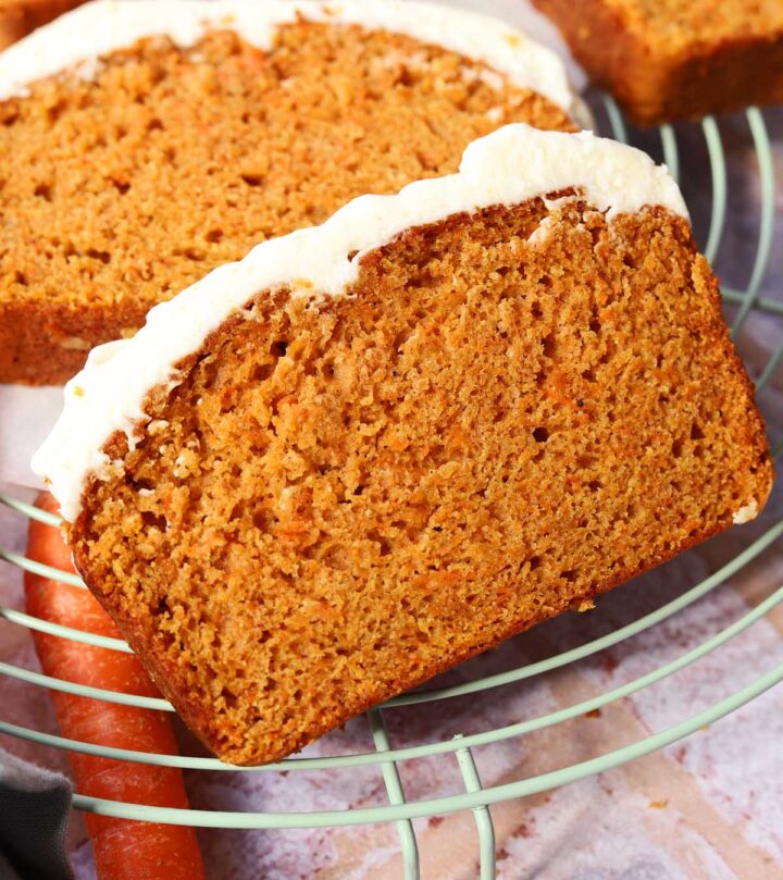 carrot cake loaf cake sliced on cooling rack with cream cheese frosting