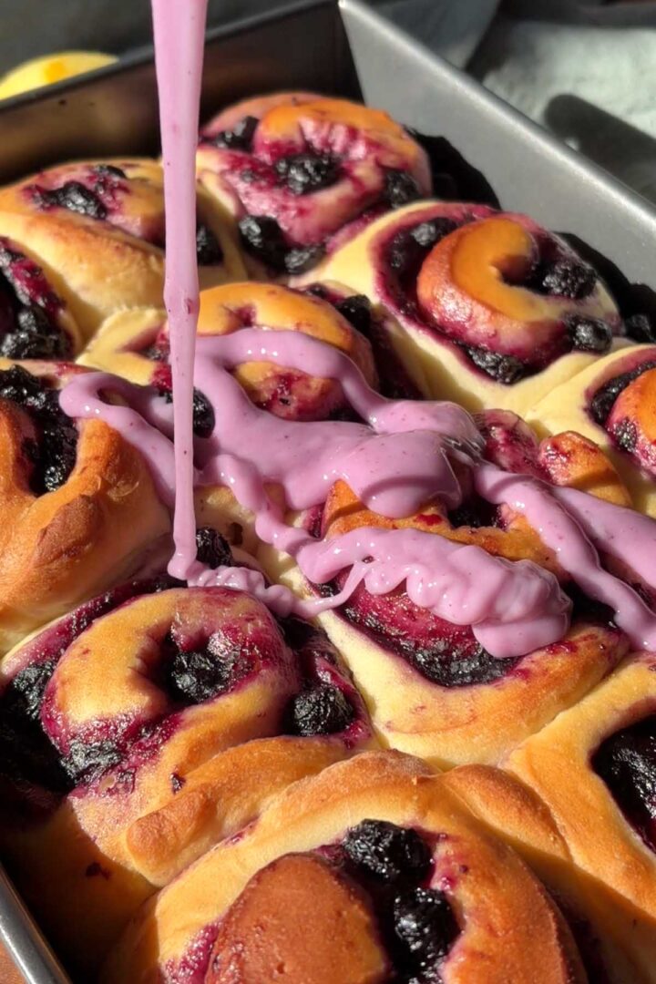 drizzling icing over lemon blueberry sweet rolls