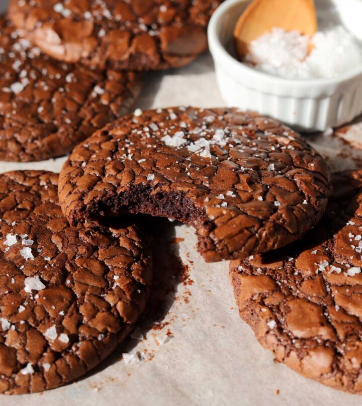 chewy crinkle top brownie cookies on stacked on baking sheet with bite