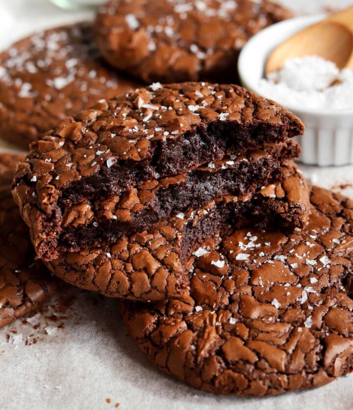 chewy crinkle top brownie cookies broken in half and stacked on baking sheet