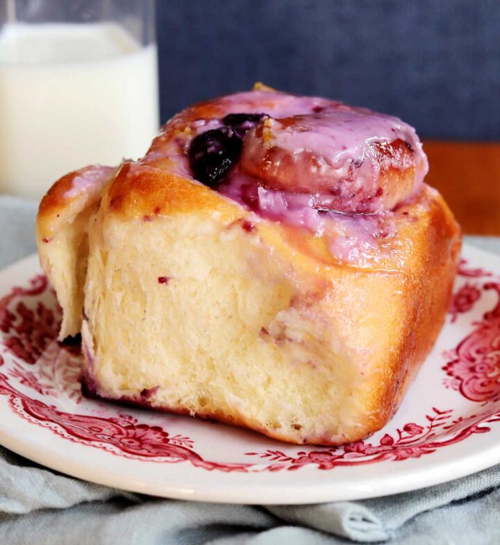lemon blueberry sweet roll on a plate with jug of milk