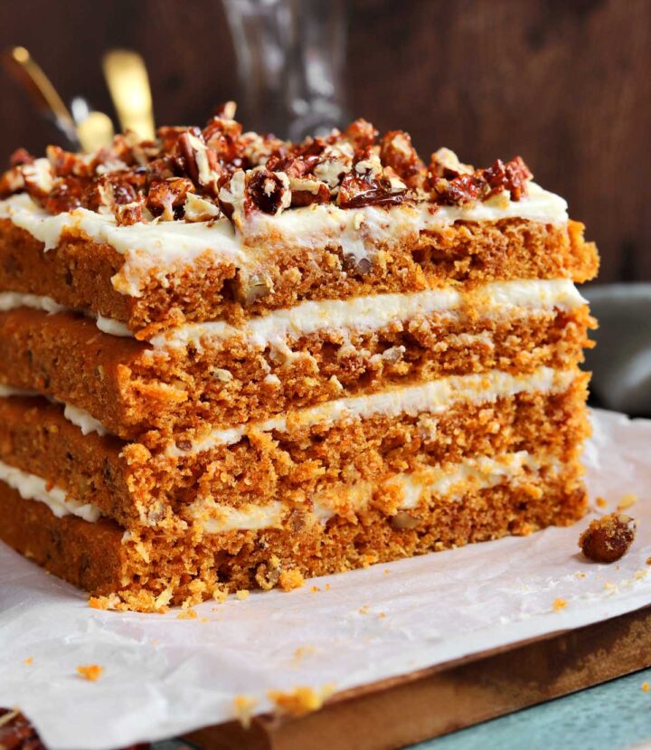 praline crunch carrot cake layer cake on a cutting board sliced showing the cross section of all 4 layers