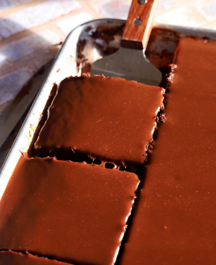 angle view of chocolate sheet cake sliced in sheet pan with cake server