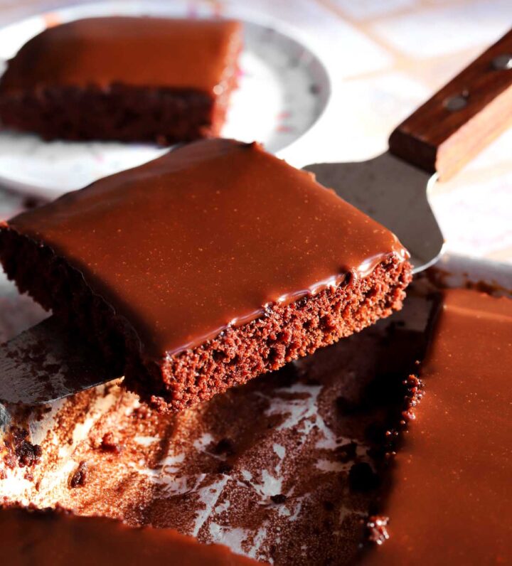 slice of chocolate Texas sheet cake on cake server over a sheet pan