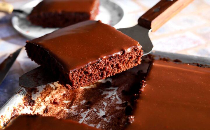 slice of chocolate Texas sheet cake on cake server over a sheet pan