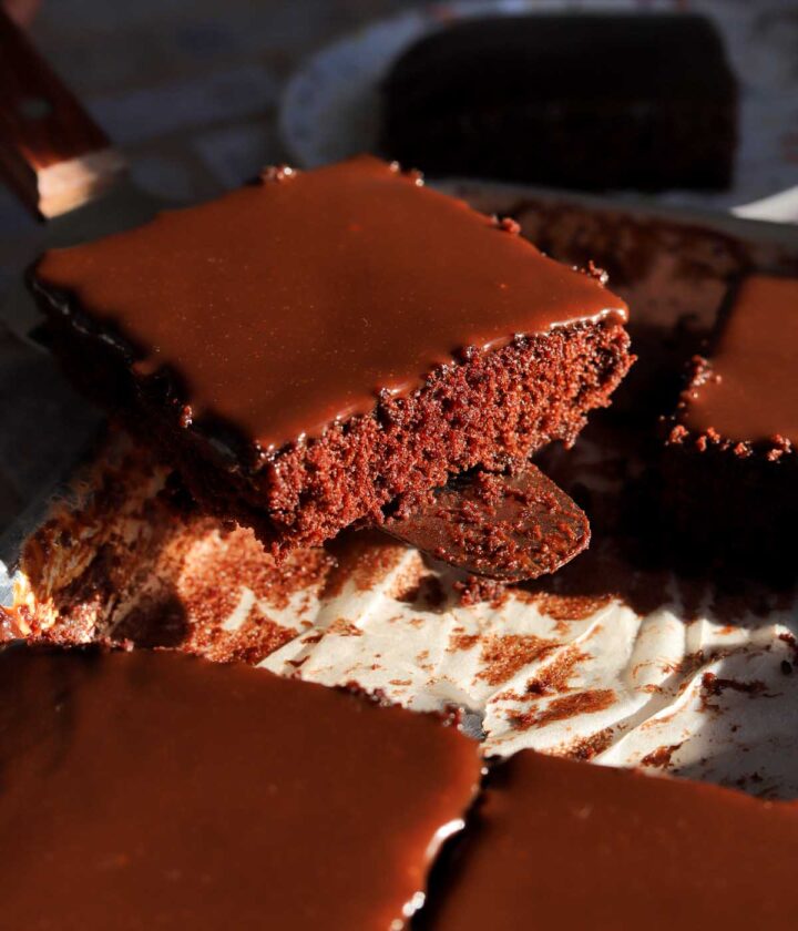 slice of chocolate Texas sheet cake on cake server over a sheet pan