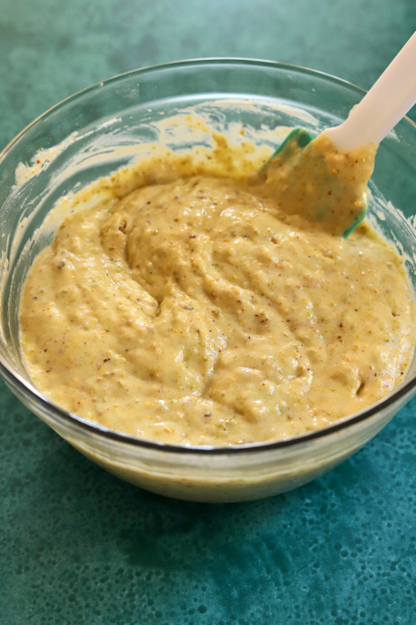 olive oil pistachio cake batter in a bowl with spatula