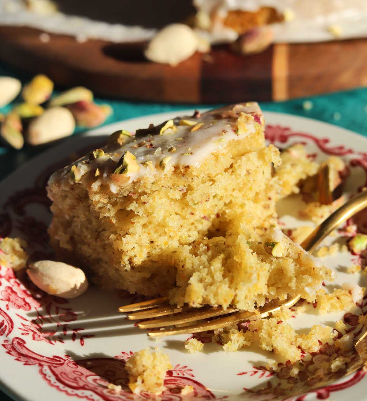 olive oil pistachio cake slice on a plate with bite and fork