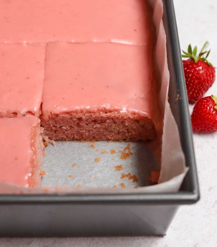 strawberry sheet cake with strawberry icing sliced in baking pan