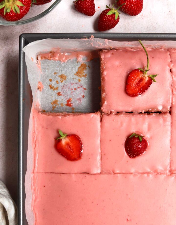strawberry sheet cake with strawberry icing sliced in baking pan with fresh strawberries