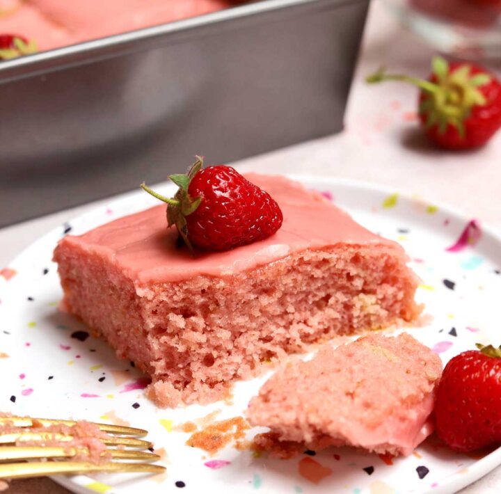 slice of strawberry sheet cake on a plate with bite and fork