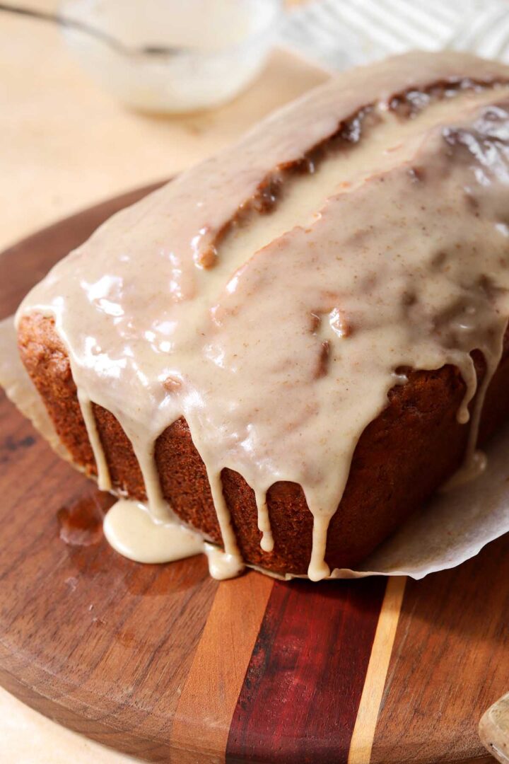 brown butter banana bread loaf on cutting board with glaze dripping down