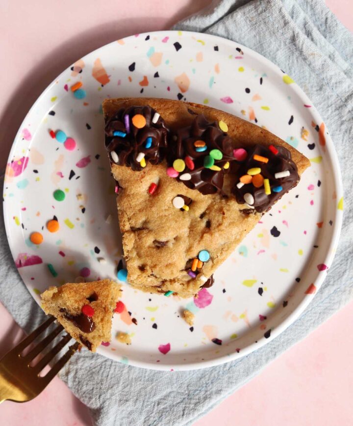 top view of slice of chocolate chip cookie cake on a plate with bite and fork