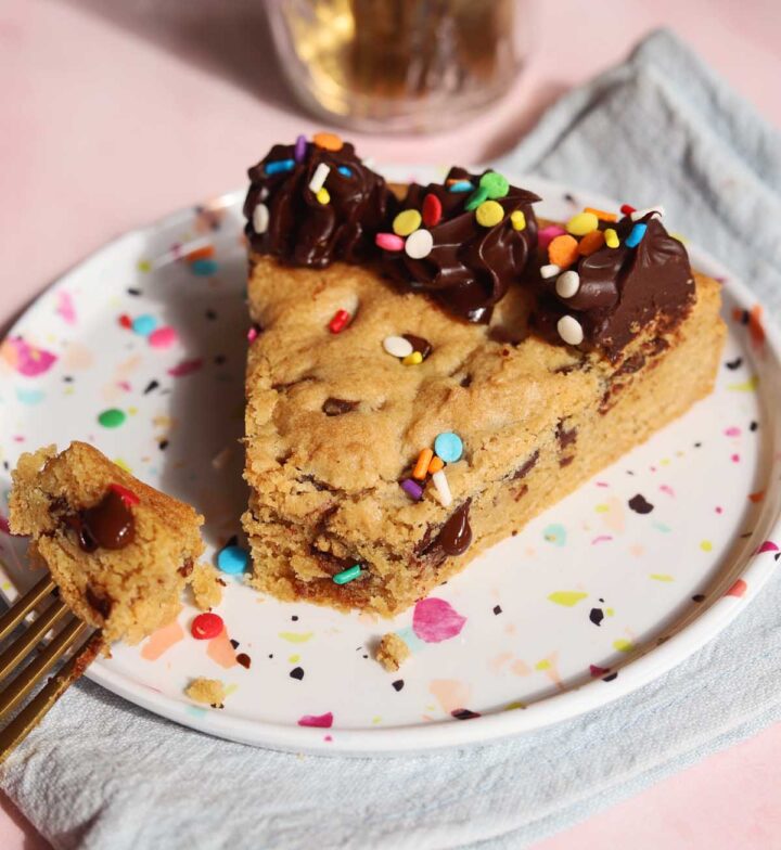 slice of chocolate chip cookie cake on a plate with bite and fork