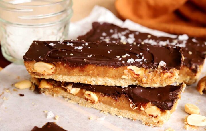 healthy snickers bars sliced and stacked on parchment paper