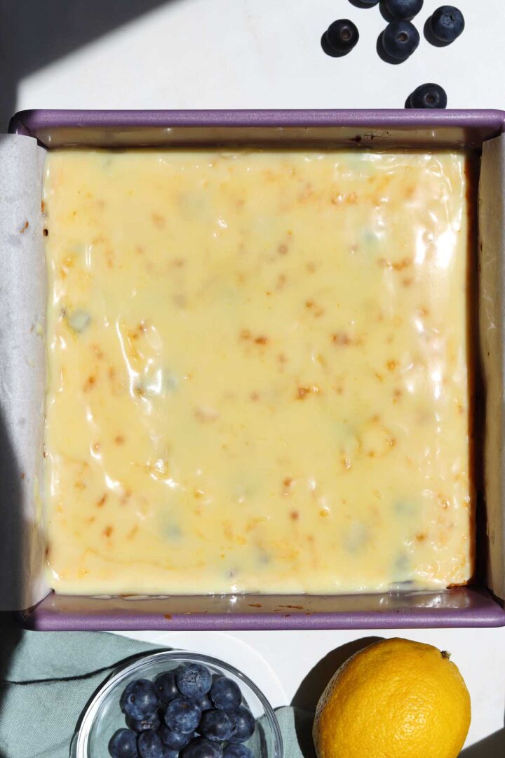 lemon blueberry brownies in baking pan after baking with lemon white chocolate icing