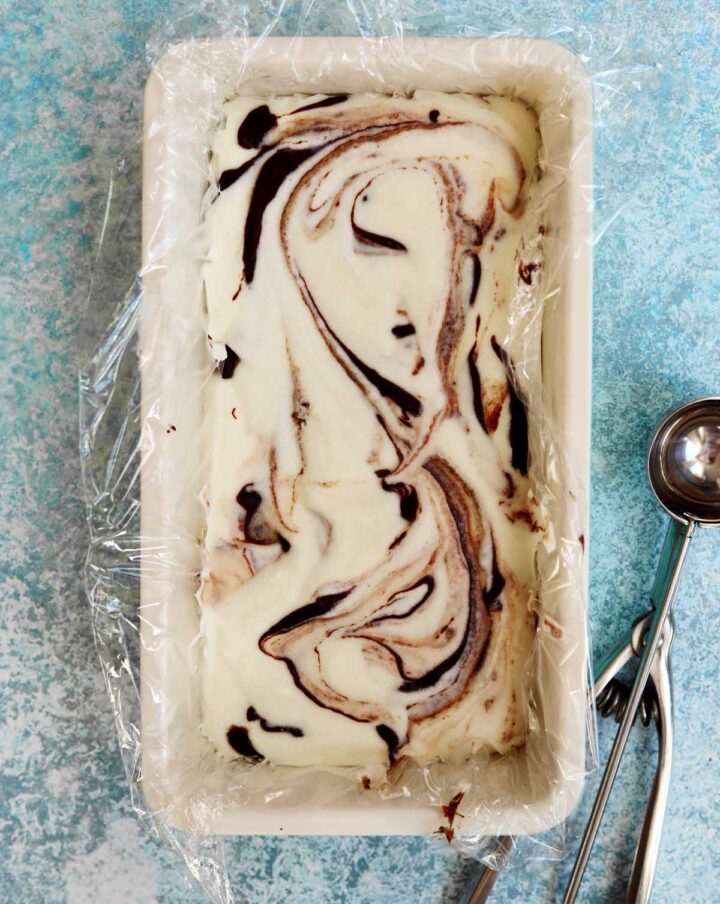 no churn chocolate fudge swirl peppermint cheesecake ice cream in loaf pan with ice cream scoop