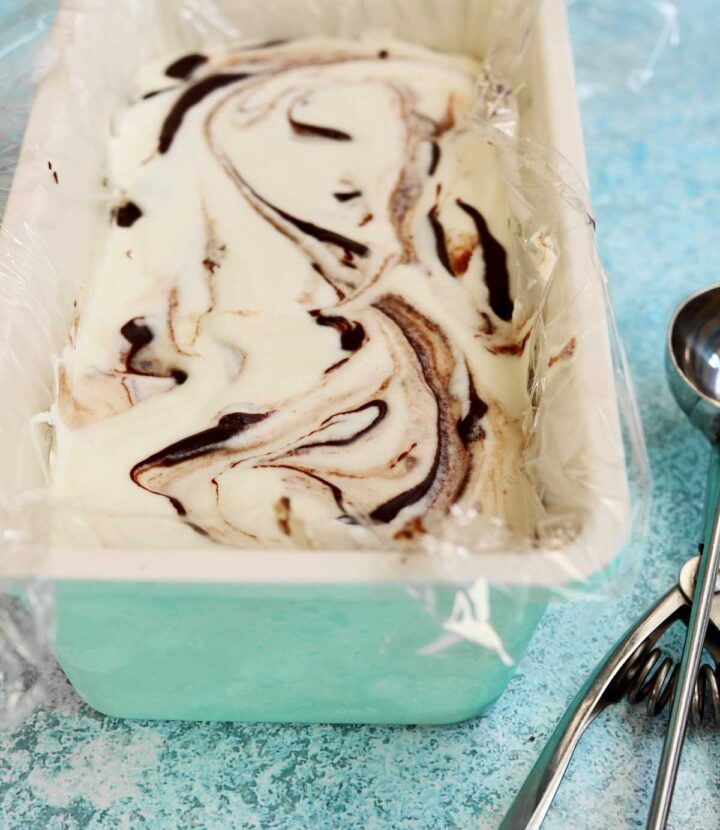 no churn chocolate fudge swirl peppermint cheesecake ice cream in loaf pan with ice cream scoop