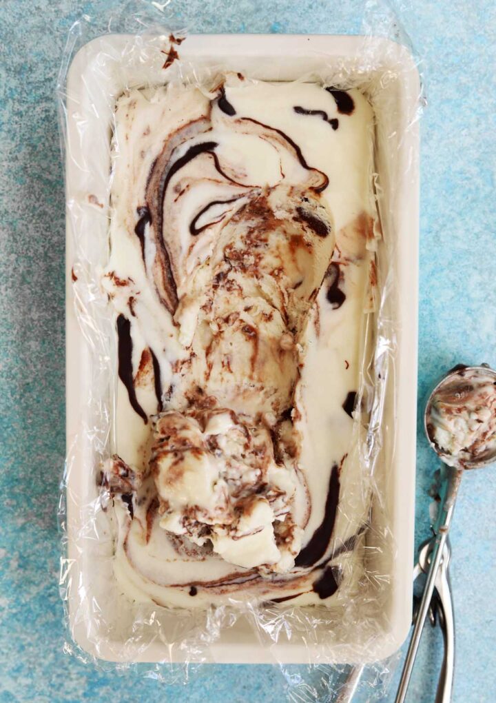 no churn chocolate fudge swirl peppermint cheesecake ice cream in loaf pan with ice cream scooped out