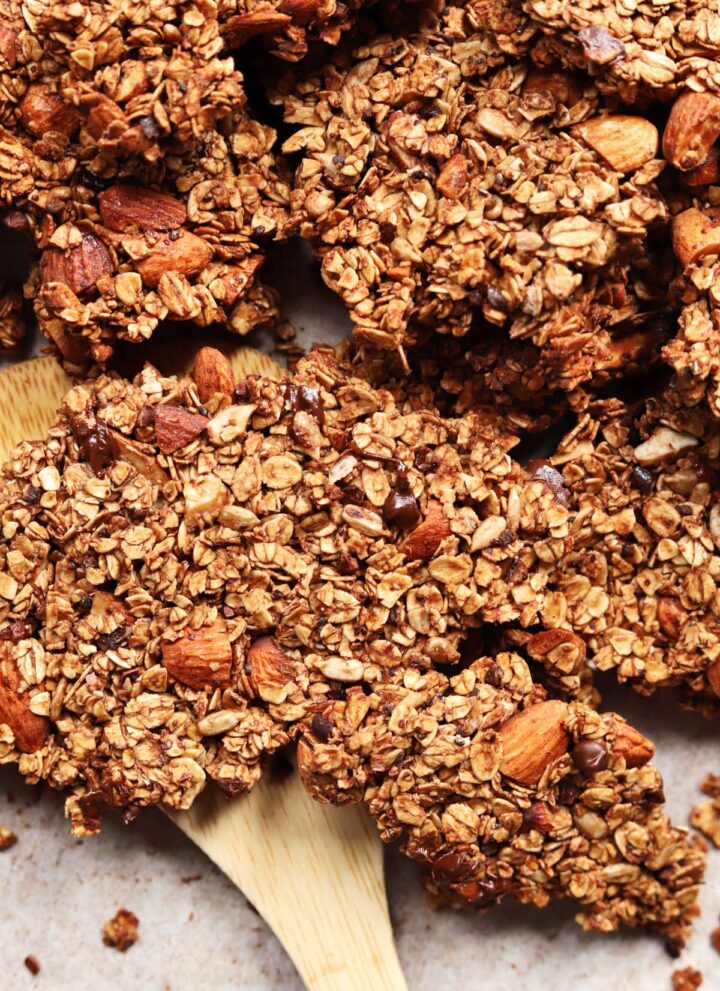 chocolate olive oil granola on a baking sheet with wooden spatula