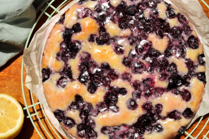 top view of lemon blueberry yogurt cake with glaze dripping down on cooling rack