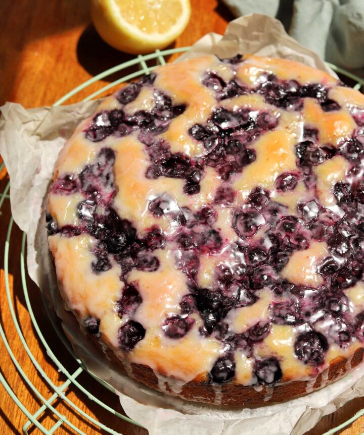 top view of lemon blueberry yogurt cake with glaze dripping down on cooling rack