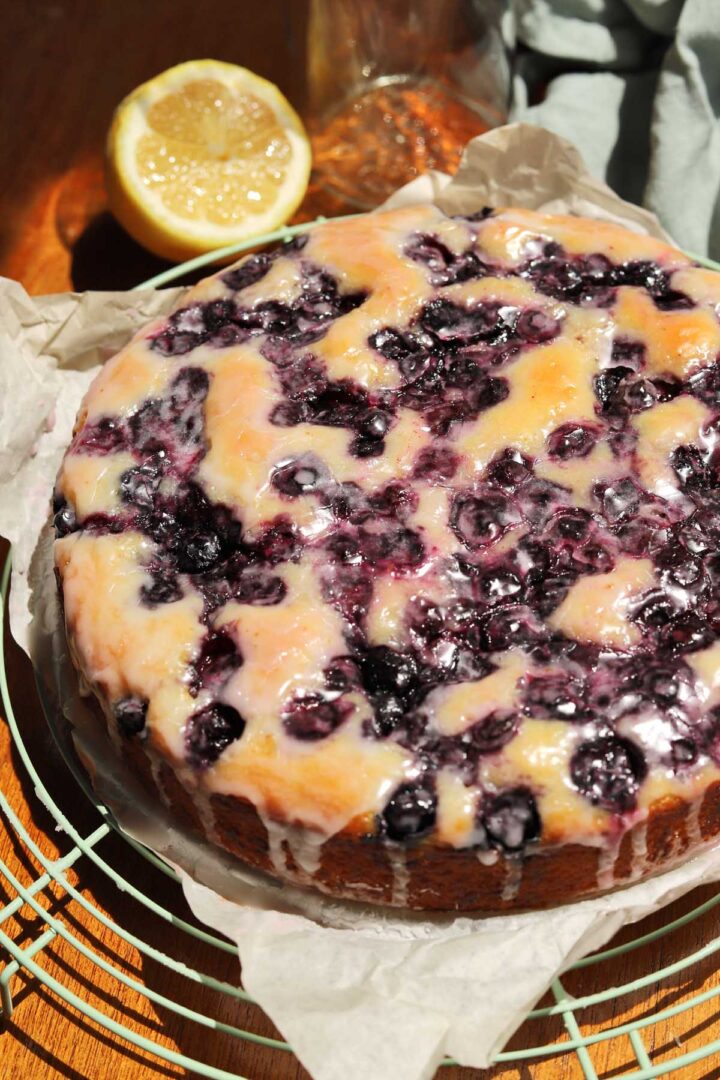 lemon blueberry yogurt cake with glaze dripping down on cooling rack