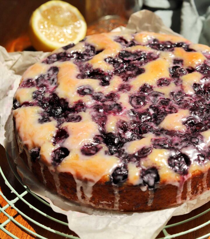 lemon blueberry yogurt cake with glaze dripping down on cooling rack