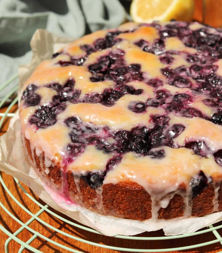 lemon blueberry yogurt cake with glaze dripping down on cooling rack