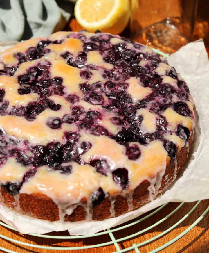 lemon blueberry yogurt cake with glaze dripping down on cooling rack