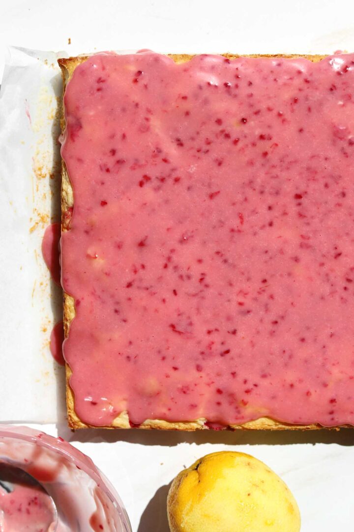 raspberry lemonade brownies on parchment with raspberry glaze