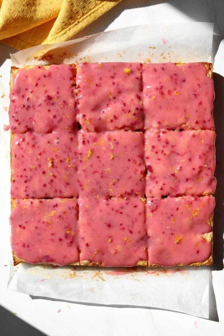 sliced raspberry lemonade brownies on parchment with raspberry glaze