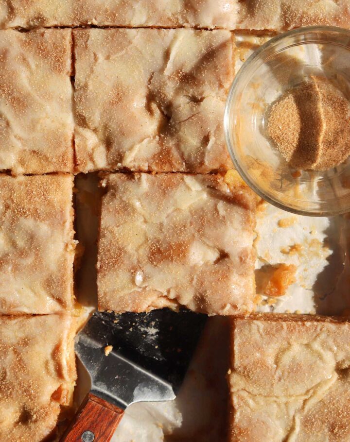 top view of apple fritter Texas sheet cake in baking sheet pan with serving spatula