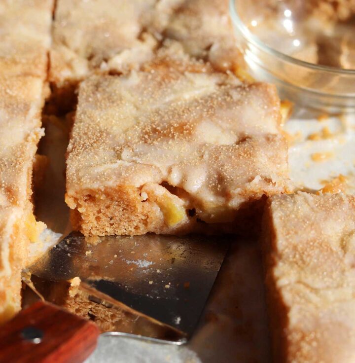 apple fritter Texas sheet cake in baking sheet pan with serving spatula