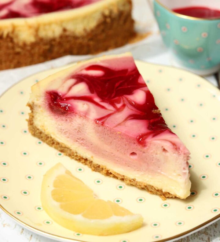 lemon raspberry cheesecake slice on a plate with lemon slice