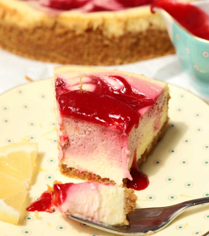 raspberry lemonade cheesecake slice on a plate with raspberry sauce and bite on a fork