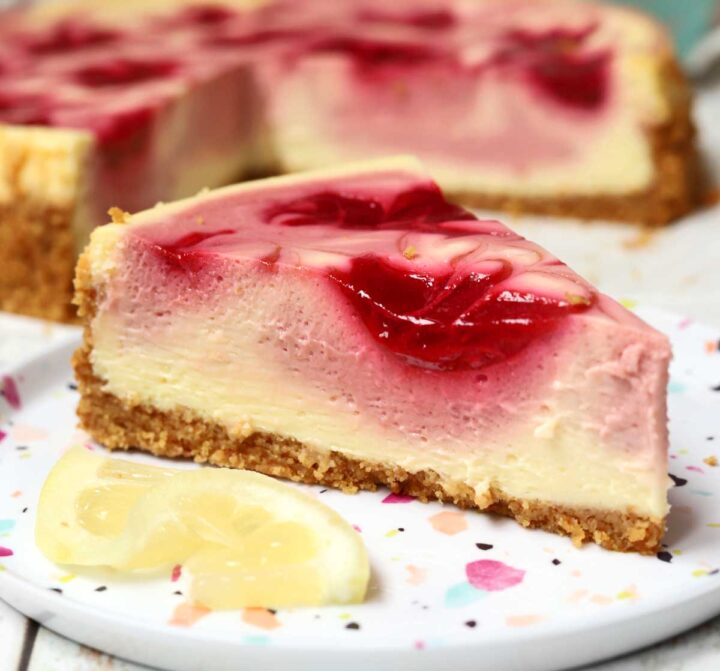 lemon raspberry cheesecake slice on a plate with lemon slice