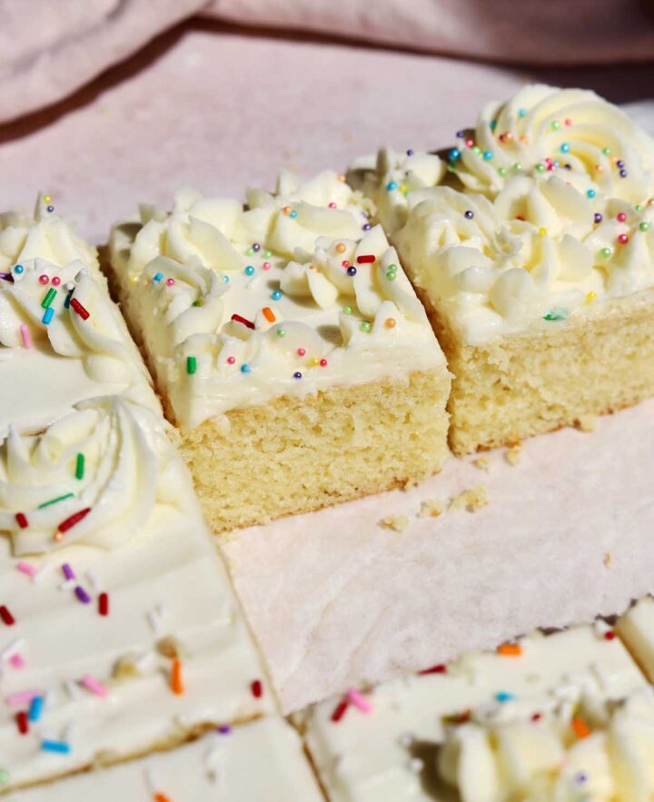 moist vanilla sheet cake sliced on parchment paper
