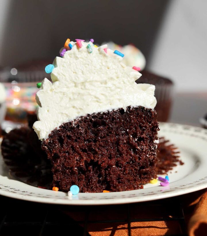best moist chocolate cupcake with the best vanilla buttercream frosting cut in half showing soft crumb and creamy fluffy frosting