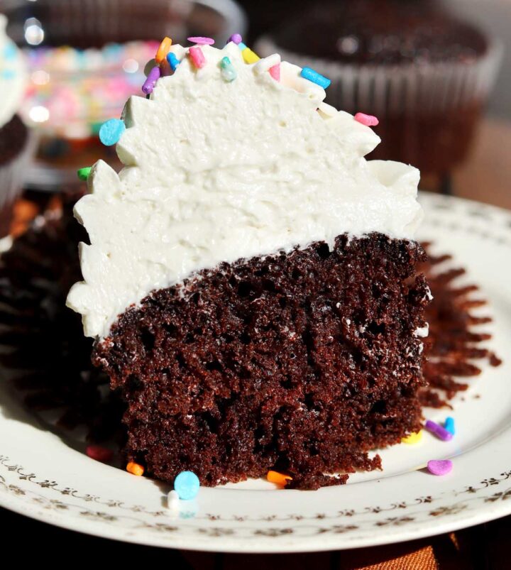 best moist chocolate cupcake with the best vanilla buttercream frosting cut in half showing soft crumb and creamy fluffy frosting