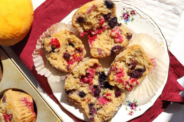 healthy olive oil Greek yogurt berry muffins split in half showing soft crumb texture and piled on a plate