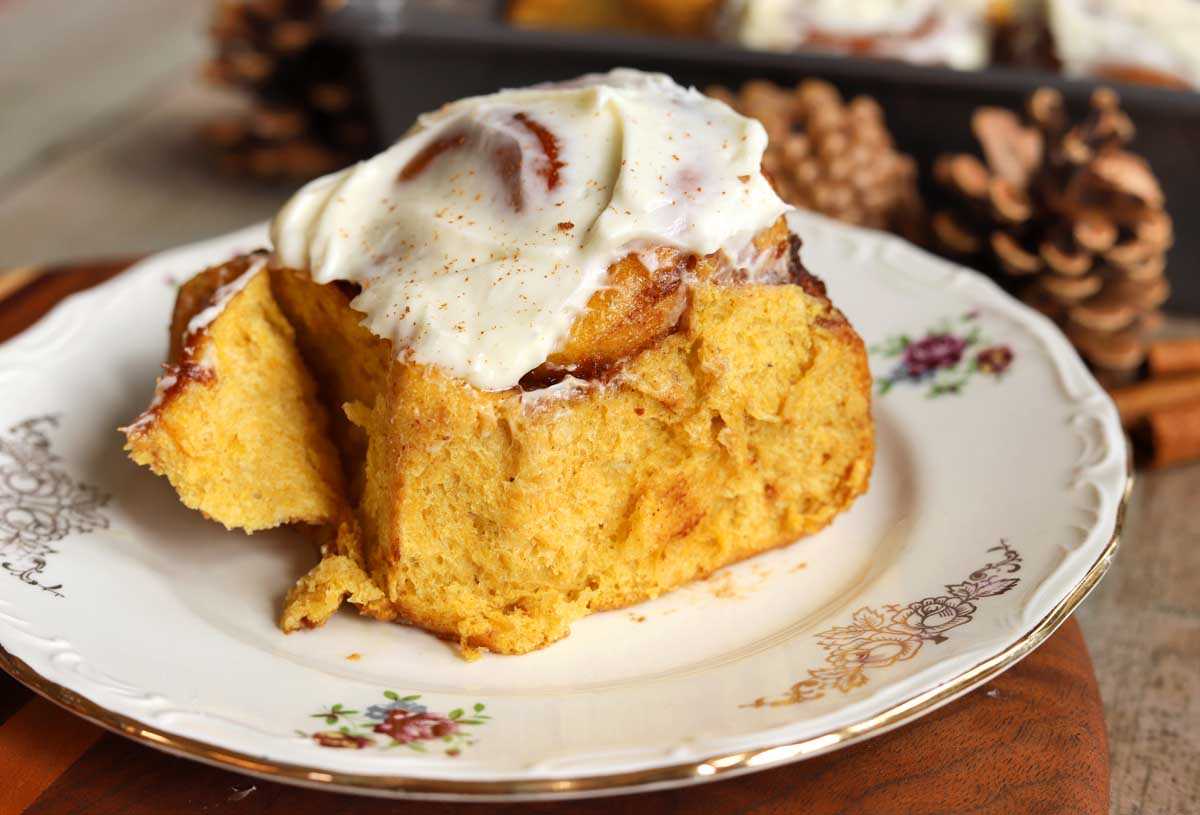 best pumpkin cinnamon roll on a plate with cream cheese icing